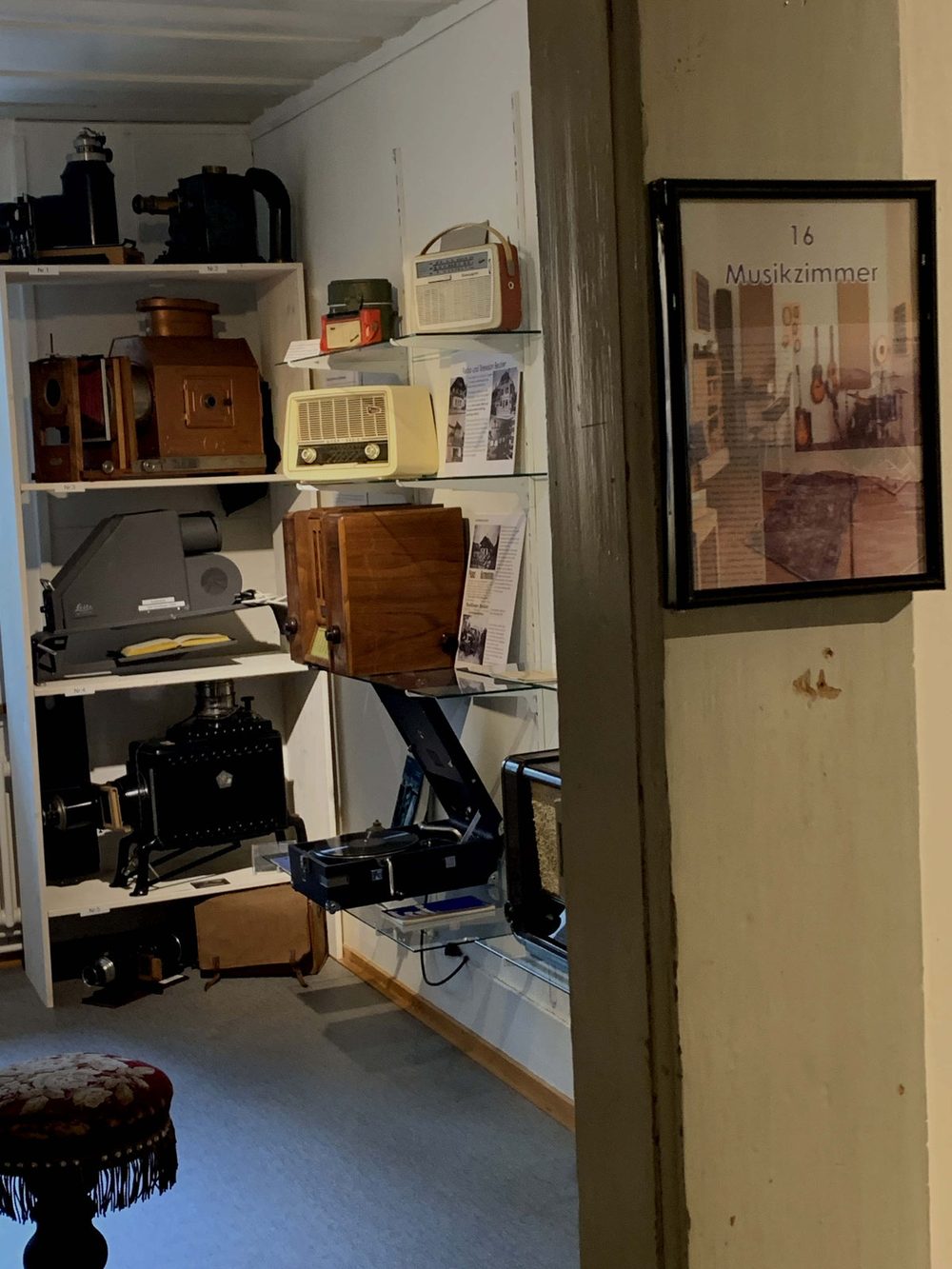 Das Musikzimmer mit Radios, Grammophonen und Musikinstrumenten in Regalen.