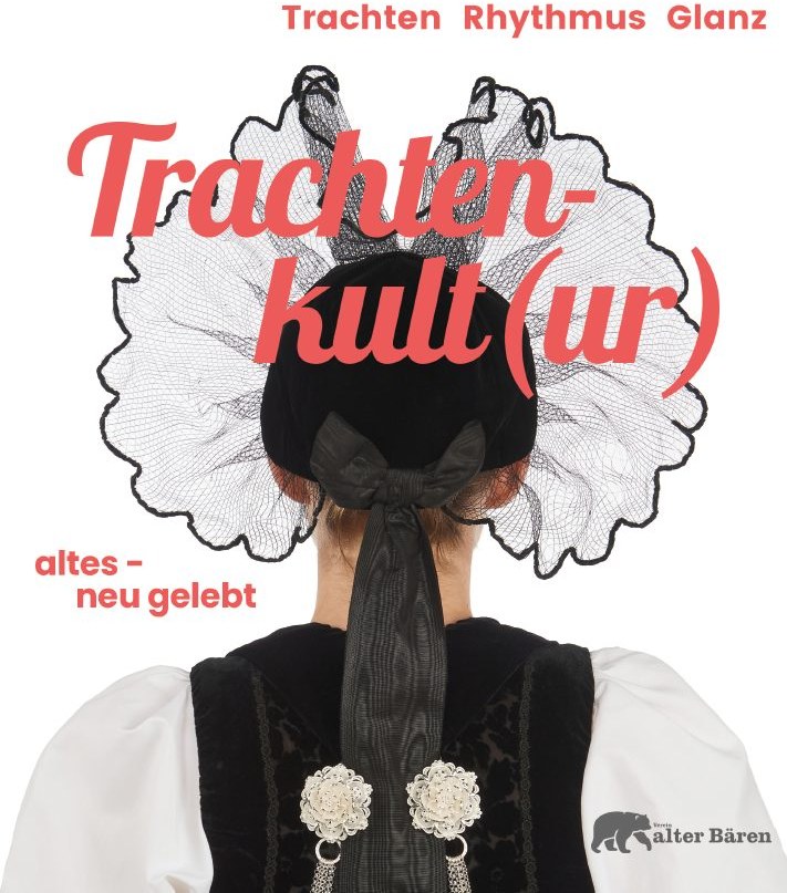 Ausstellungsmotiv Trachtenkult(ur): Rückenansicht einer Trachtenträgerin mit weisser Spitzenhaube und Filigranschmuck.